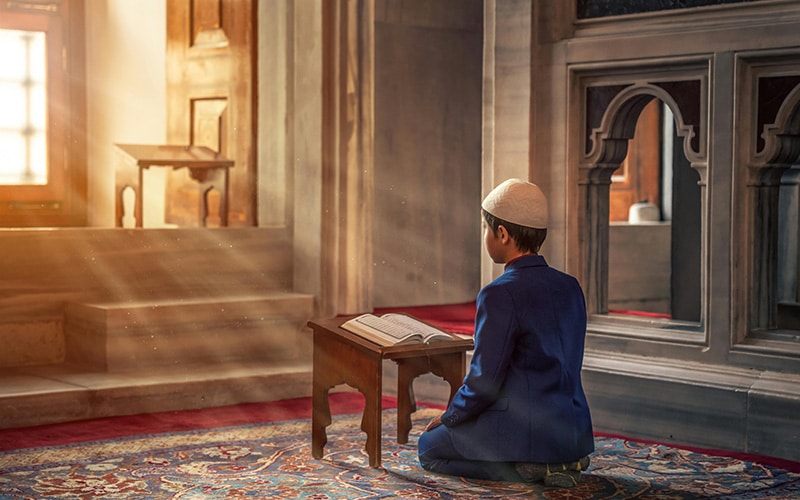 young child reading prayer book during the Holy Month of Ramadan