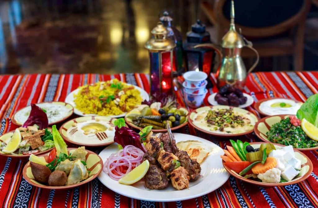 Iftar table featuring a variety of traditional dishes such as dates, samosas, grilled meats, and lentil soup